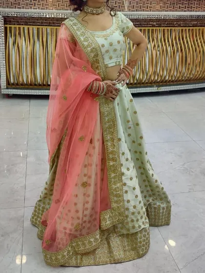 This elegant pista green lehenga with a contrasting peach dupatta is a popular rental for daytime events and sangeet functions. The light color and delicate gold motifs create a fresh and sophisticated look.