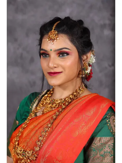Another angle of the orange and green saree look, capturing a direct and engaging gaze. The studio lighting ensures the colors of the saree are true and vibrant.