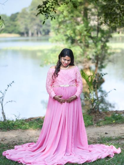 A peaceful lakeside portrait of a mom-to-be in a lovely pink lace-top gown. The natural setting provides a calm and beautiful backdrop.