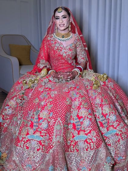 Seated and serene, this bride looks like royalty. The rich colors of her outfit are echoed in the warm tones of her makeup, creating a harmonious and elegant bridal look.