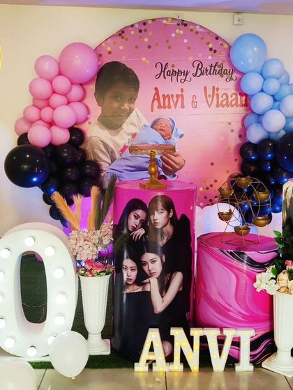 A joint 10th and 1st birthday celebration with a K-Pop and Boss Baby theme. The decor features a Blackpink cutout, a Boss Baby plinth, and large light-up numbers.