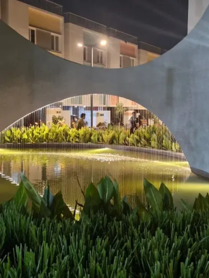 A sculptural water feature serves as a focal point in this residential community in Bangalore. The interplay of light, water, and concrete creates a dramatic and serene atmosphere in the evening, demonstrating how landscape elements can define a space.