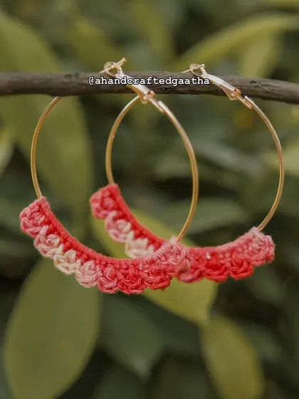 A beautiful shot of the crimson 'Naazakat' hoops hanging in nature. The gold hoop adds a touch of elegance to the rustic cotton yarn.