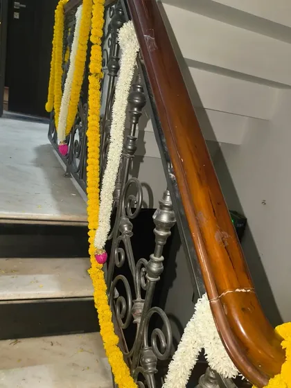 A classic staircase railing decorated with alternating garlands of marigold and jasmine for a traditional festive look.
