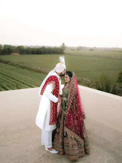 A tender moment between the bride and groom on a rooftop overlooking lush green fields. A perfect blend of intimacy and a beautiful destination wedding landscape.
