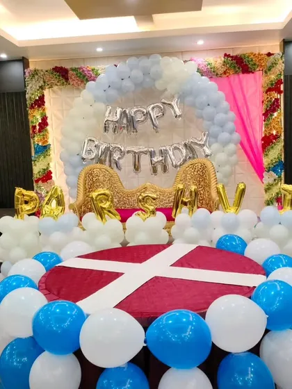 A classic first birthday setup in a restaurant. We created a stage with a large balloon semi-circle, "Happy Birthday" foil letters, and the baby's name in gold, making a perfect spot for photos.