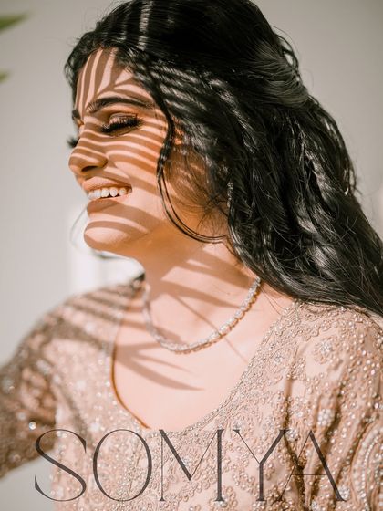 A creative bridal portrait using the shadow of a palm leaf to create a beautiful pattern of light on her smiling face.