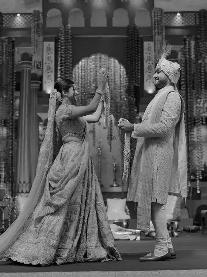 Tanya and Shivam during their varmala ceremony. Her joyful attempt and his playful bow create a dynamic and happy moment, showing the fun that can be had even during formal rituals.