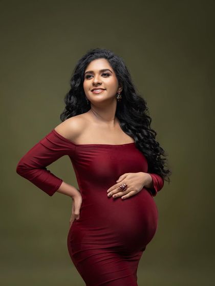 A classic portrait in a deep red off-the-shoulder gown. The rich color and simple olive backdrop create a warm and intimate feel.