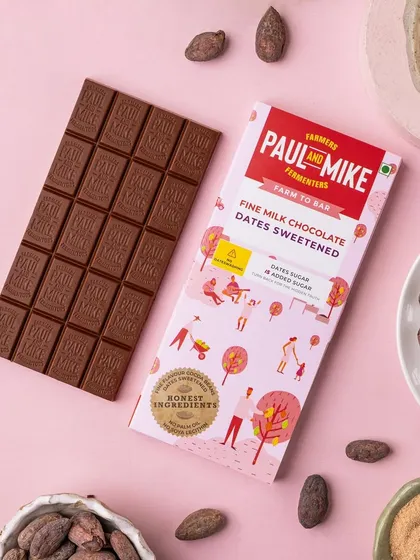 A product shot of a milk chocolate bar on a soft pink background. The colour choice complements the packaging and gives the image a gentle, sweet feel.
