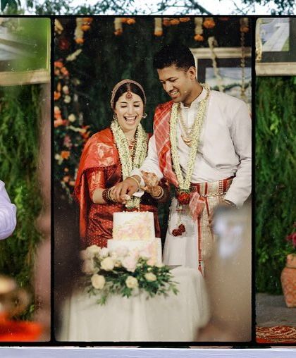 The couple cutting their cake at their Coorg wedding, a sweet moment amidst the traditional red and white attire of the region.