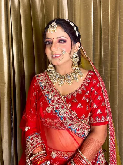 A happy bride showing off her complete look. The combination of her red lehenga, kundan jewelry, and my flawless makeup application results in a picture-perfect bridal moment.