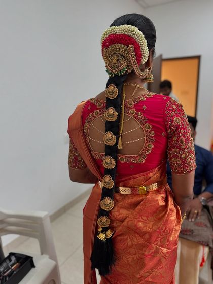 A detailed view of Abi's traditional bridal hairstyle. The braid is decorated with temple-style jewellery pieces and a red floral veni, creating a rich and authentic look.