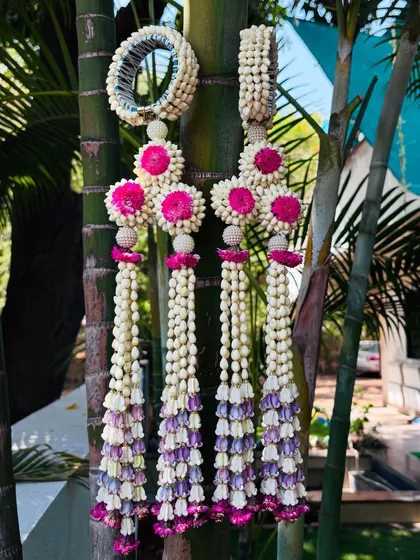 Adorn yourself with elegance. These are floral hathphool with long, cascading kalire, made with mogra buds and accented with pink and purple flowers.
