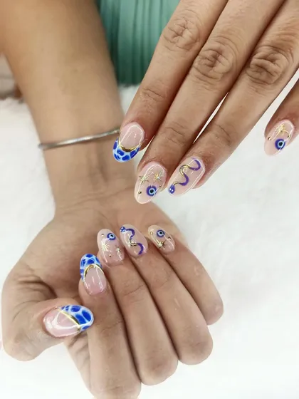 Ward off bad vibes with this stylish evil eye nail art. This design features hand-painted evil eye symbols and abstract blue patterns, accented with delicate gold lines for a modern twist.