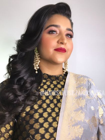 A glamorous side-swept open hairstyle with big, bouncy curls, perfect for a party.