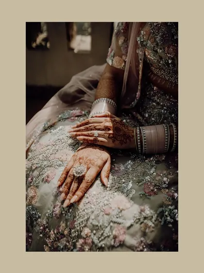 A close-up shot of the bride's hands, showcasing her intricate henna and wedding ring.