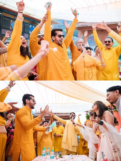 The entire guest list, dressed in yellow, raises their hands in celebration, showing the collective energy of a fun Haldi party.