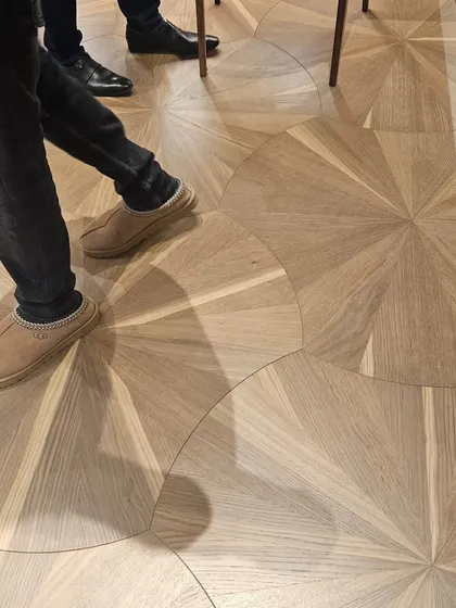 Another view of the radial-patterned wooden floor, showing how it interacts with light and shadow to create a dynamic surface.