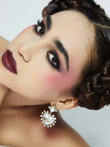 A dramatic look with bold brows, heavy blush, and a deep, vampy lip, showcasing a more theatrical style of makeup.