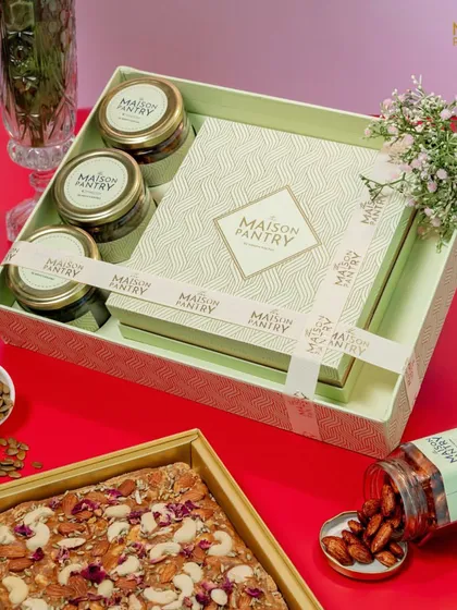 This beautifully arranged hamper showcases how I combine different elements for a complete gift. It includes a large mithai box, savory nut jars, and is tied with a custom ribbon, all nestled in a reusable tray.