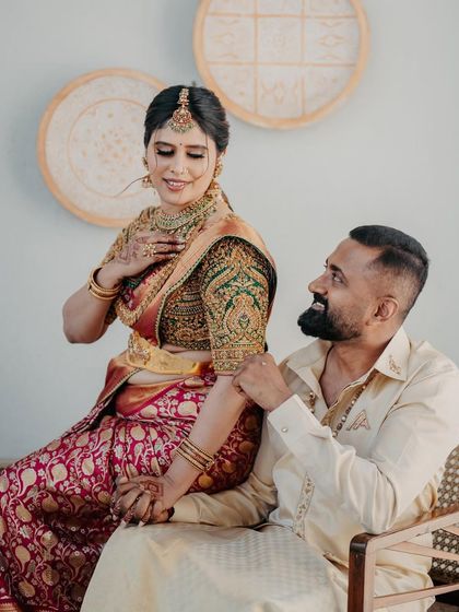 An intimate moment between a couple. The groom's hand on her arm draws attention to the detailed zardozi work on her green blouse sleeve, a hallmark of our craftsmanship.