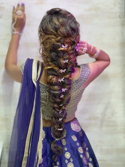 A back view of the intricate and voluminous messy braid, decorated with small butterfly clips.