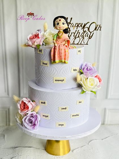 Celebrating 60 graceful years. This two-tier cake is a tribute to a mother, decorated with words in Marathi that describe her wonderful qualities, and topped with a custom fondant figure.