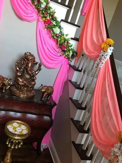 I also decorate indoor spaces like staircases. Here, I used bright pink drapes and floral garlands to adorn the railing, ensuring the festive decor flows throughout the home.