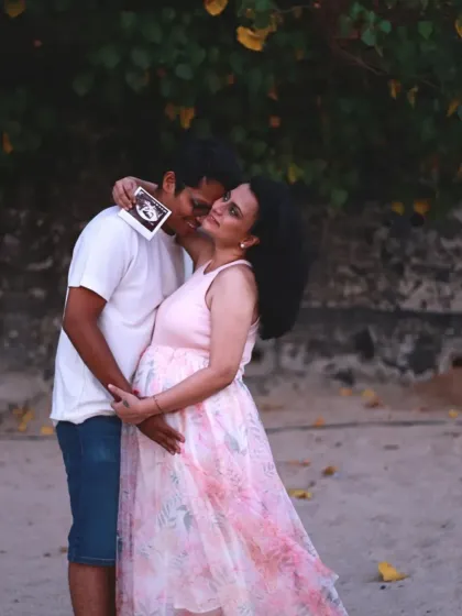 A truly special moment on the beach where the father-to-be kisses his partner's cheek while she holds up their baby's ultrasound picture.