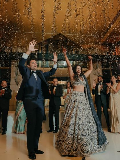 The couple makes a grand entrance to their reception, hands in the air, as confetti rains down. This shot is pure celebration and joy.
