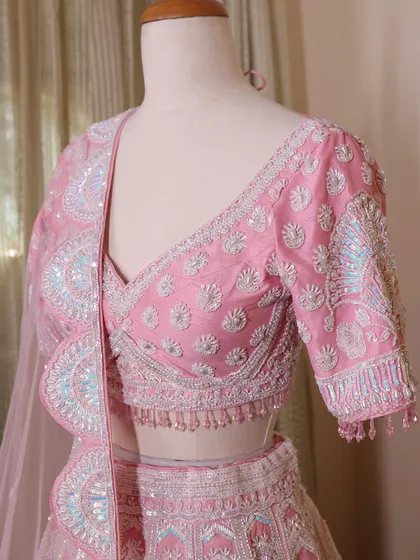 A close-up of the pink lehenga's blouse, highlighting the intricate sequin and thread work. The craftsmanship is what makes my pieces special.
