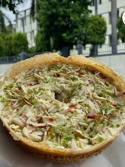 A close-up of my Malai Ghewar, generously topped with sliced almonds and pistachios. It’s the authentic taste of Rajasthan, made fresh right here.