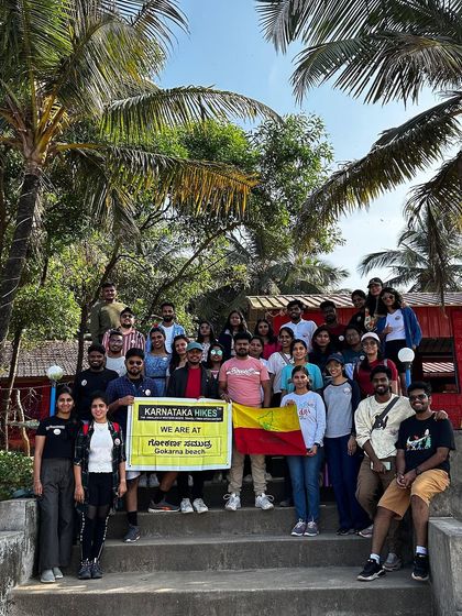 Our group posing with the banner at Gokarna beach, with the beautiful palm trees framing the shot.