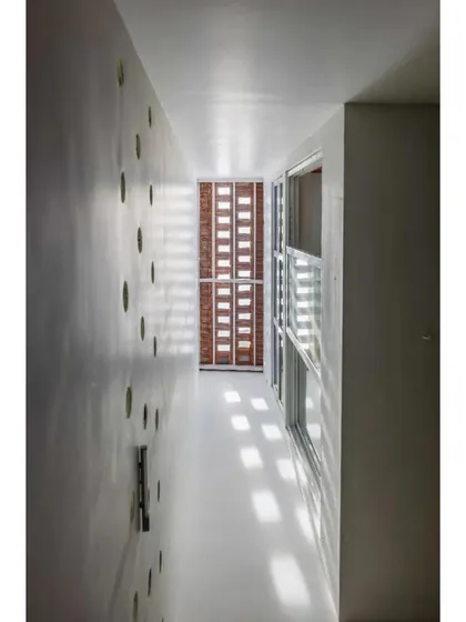 Light enters the narrow home through circular openings in the wall, demonstrating a creative solution to the challenges of a compact, dense site.