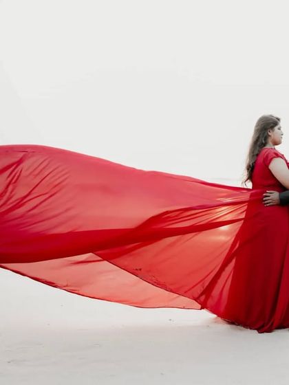 The contrast of this vibrant red long-trail gown against the white sand makes for a breathtakingly beautiful pre-wedding photograph.