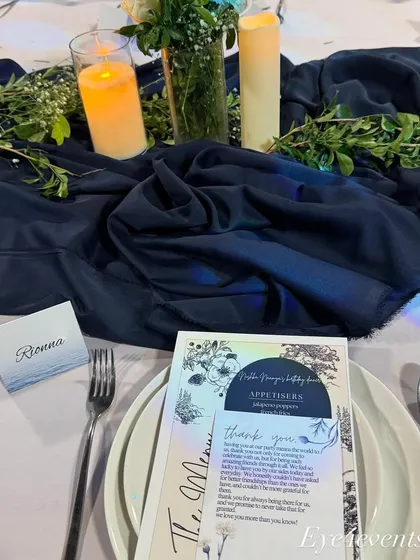 A personalized place setting from a blue and white themed event. The custom menu and name card feature elegant typography and design elements that complement the overall decor, making each guest feel special.