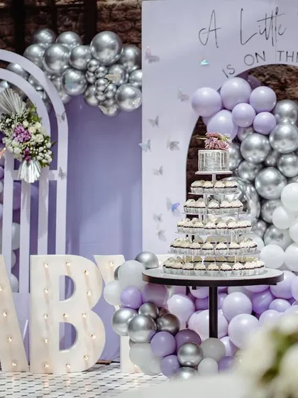 The full cake and decor setup, featuring a cupcake tower perfectly integrated into the lavender and silver butterfly-themed backdrop.
