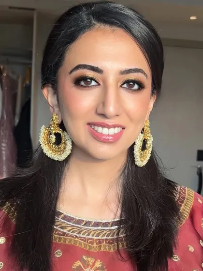 A perfect example of our signature wedding guest glam. This look features a warm, golden smokey eye and a glossy nude lip, beautifully complementing the client's traditional attire and statement earrings.