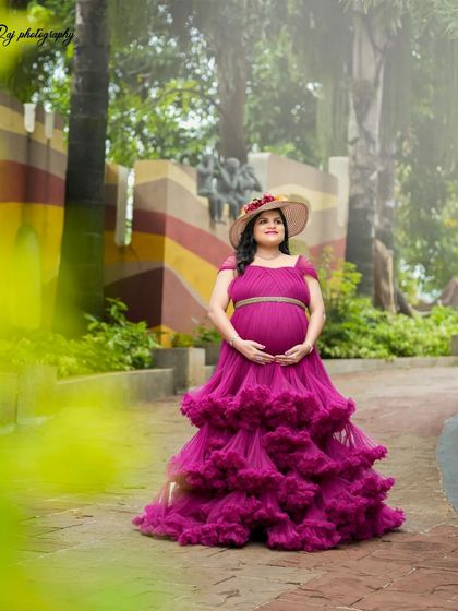 A beautiful portrait of an expecting mother in a purple ruffled gown, looking regal in our outdoor setting.