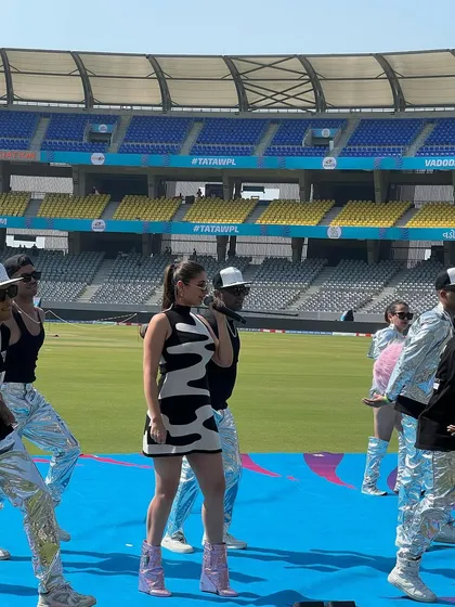 Sound check style. Dhvani Bhanushali rehearsing for a stadium performance in a cool black and white patterned dress and metallic pink boots, getting the vibe right before the show.