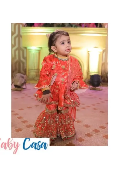 A little girl looking stunning in a traditional sharara suit for a Lohri celebration. The bright colors and gota work make it a perfectly festive choice.