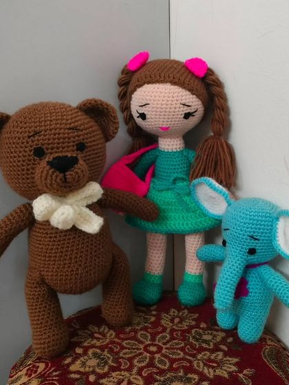 A cute doll with her two best friends, a little blue elephant and a brown teddy bear.