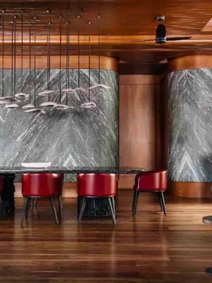 In this Bengaluru residence, the dining area becomes a canvas for material richness. We juxtaposed bold green marble against warm wood and vibrant red chairs, using custom pendant lighting to create a sense of depth and resonance between space and memory.
