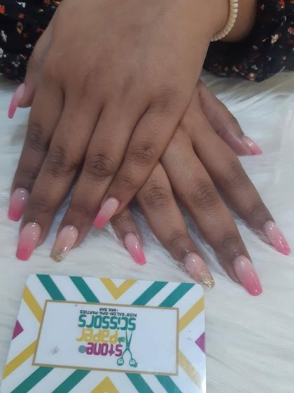 A classic pink ombre on long coffin-shaped nails. This set features a seamless blend from soft nude to a pretty pink, with one accent nail in a subtle gold glitter.