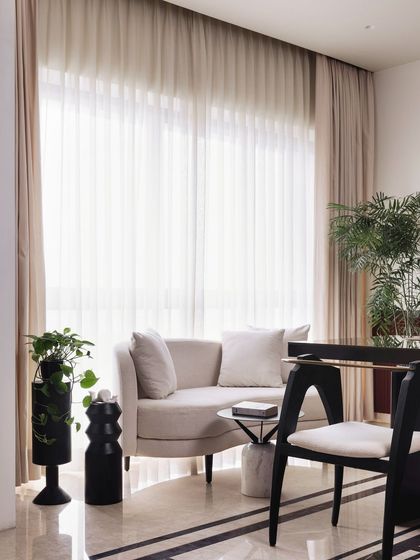 A small, curved sofa provides a comfortable spot for breaks within the home office. The space is designed to be both productive and relaxing, with plenty of natural light from the large window.