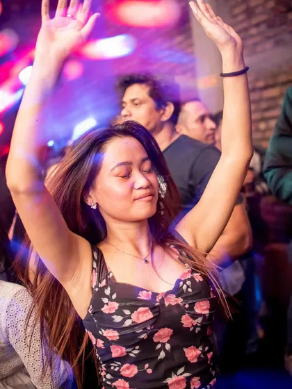 A guest with her hands up, lost in the music.