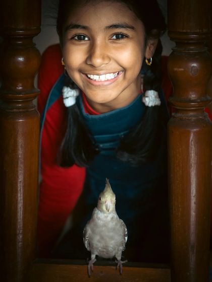 A moment of pure joy between a girl and her cockatiel, framed by the wooden railings of a staircase. This shot shows how we can find beautiful compositions right inside your home.