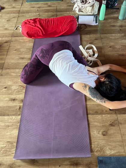 A student in a supported child's pose, using a bolster to allow for complete relaxation of the back and shoulders.