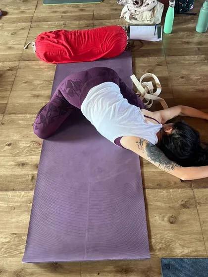 A student in a supported twist, using a bolster to find ease and release in this restorative Yin posture.